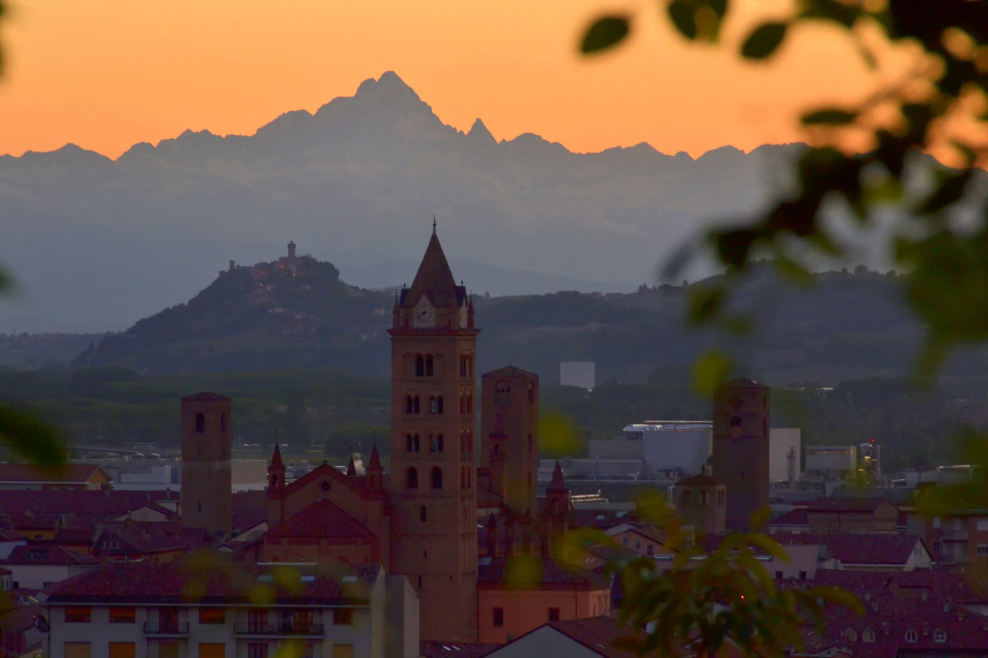 The bell towers of Alba silhouetted against the Alps at sunset