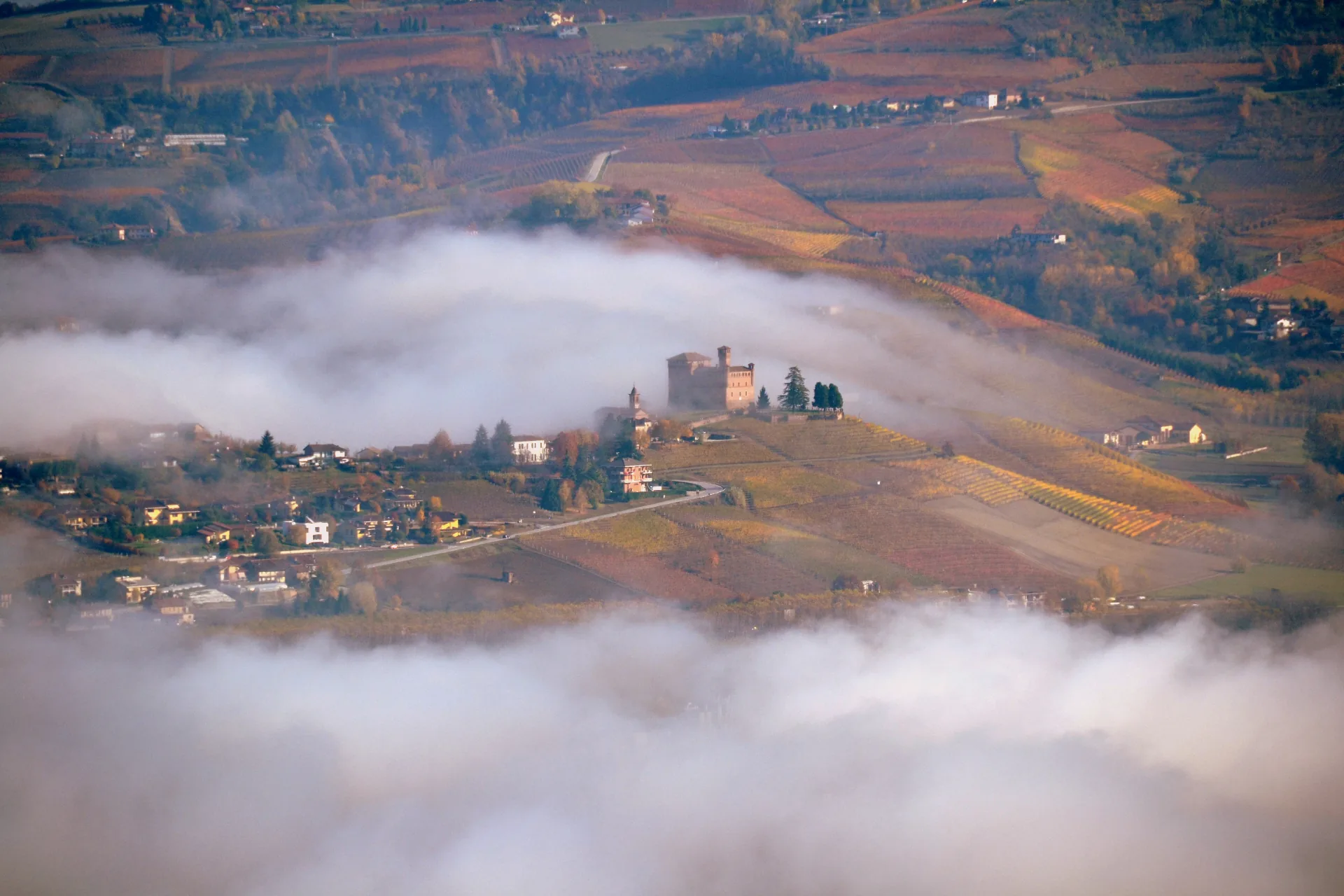 Castello di Grinzane Cavour rising above the morning fog over the Langhe vineyards